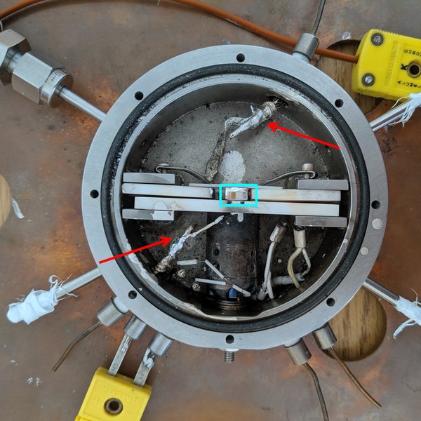 Top-down view of the in-situ chamber with a planar CeO₂ device mounted between electrical contacts.